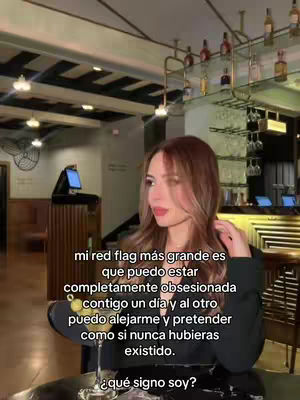 The image shows a woman with long brown hair, posing in a bar or restaurant setting. She is holding a cocktail, and text overlays are placed on the image, discussing a red flag regarding obsession.