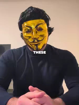 A person wearing a golden Guy Fawkes mask is centered in the frame. The person is wearing a black top, and the background is a neutral beige color. The word 'THESE' is overlaid on the image in a white box.
