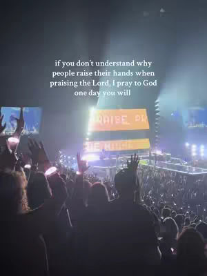 A large crowd with their hands raised in a concert setting. In the background, there's a stage with bright lights and a sign that says 'RAISE PR' in large letters. The sky is dark with a text overlay written in white color.