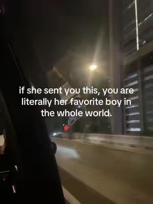 A nighttime shot looking out of a car window, showing a road and buildings with bright lights. Text overlays are featured in the image.