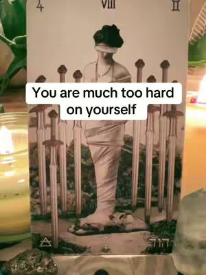 The cover image is of a tarot card illustrating the '8 of Swords' card. At its center, the card shows a veiled figure surrounded by swords with the overlaid text that says, \"You are much too hard on yourself\". The composition includes surrounding elements, such as candles and possibly other spiritual items, suggesting a tarot reading setting.