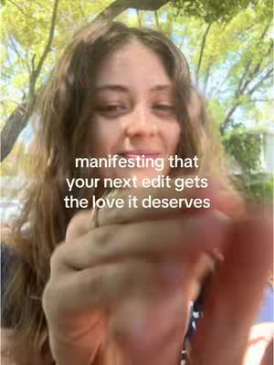 The cover image features a young woman with long, wavy hair. She is in the foreground, with a blurred hand in the frame seemingly holding the camera, and the woman appears to be looking at the camera. The background is blurred, but suggests an outdoor setting with some greenery, likely trees and foliage, and the lighting appears to be daylight. The overlay text uses a white font.