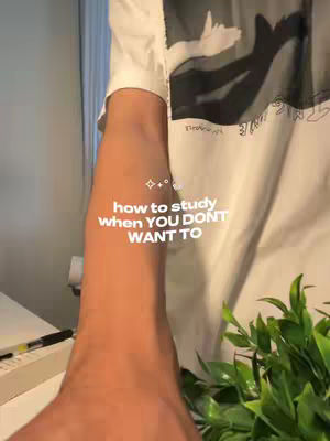 The cover photo shows a close-up from the elbow down, with the creators arm taking center stage the fore arm points to the bottom right with white text that reads how to study when you dont want to. The creator is wearing a white t-shirt and some green plants. The background is a wall and some window.