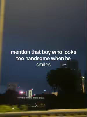 A nighttime cityscape is visible through a vehicle's window, with bright lights and dark silhouettes suggesting a urban environment. Text overlayed onto the image reads, "mention that boy who looks too handsome when he smiles."