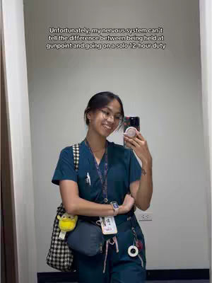 The image shows a woman taking a selfie in a mirror. She's wearing glasses, a dark teal scrub top and pants, and carrying a black and white checkered bag. She has a phone in her hand and is smiling. Text is overlaid at the top, referencing the nervous system and a solo 12-hour duty.