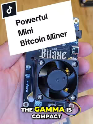 A hand holding a black circuit board with a fan and the text overlay 'Powerful Mini Bitcoin Miner'. The board has the Bitaxe 601 logo and buttons. At the bottom is the text 'The Gamma is Compact'. A TikTok logo is in the upper left corner.