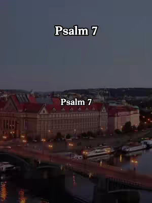An aerial view of a cityscape at dusk. The foreground features a bridge and a river, with lights reflecting on the water. Buildings with red roofs and illuminated windows line the banks. The sky transitions from dark blue to a more neutral tone. Text overlays with the title 'Psalm 7'.