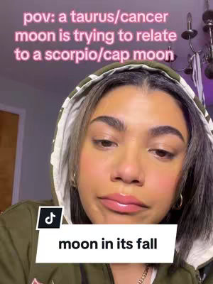 The cover image shows a young woman with dark hair and a green hoodie. The text overlay indicates that the video is about astrology. The woman has a slightly surprised, contemplative expression. The background includes a blurred interior setting with a dim light.