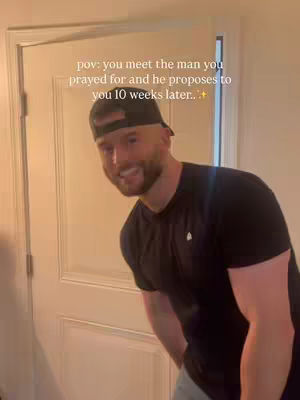 The cover image shows a man in a black shirt and a baseball cap, leaning toward the camera with a smile. The background hints at an interior setting, possibly a hallway, with a door partly visible. Text overlayed on the image reads 'pov: you meet the man you prayed for and he proposes to you 10 weeks later...+'. The overall composition is bright and the man seems very happy.