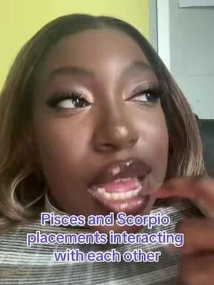 A close-up shot of a Black woman looking off to the side, seemingly mid-sentence. The background is blurred, with visible sections of a yellow wall on the left and a light-colored wall on the right. She has long, dark hair with blonde highlights, full lips with dark lip color, and long eyelashes with dark eye makeup. Text overlays the bottom portion, and a striped shirt is visible.