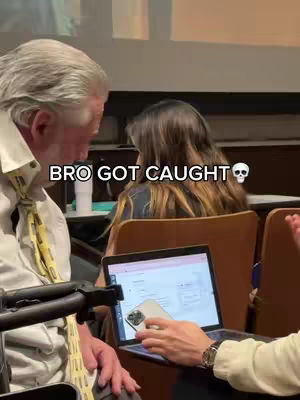 The cover image shows a lecture hall setting with an older man in a white shirt and yellow tie on the left side; he is looking at something off-camera. Beside him on the right is a person with long brown hair, seen from the back, and in between, a hand holds a phone above a laptop, implying someone is using their phone during the lecture. The text overlay reads 'BRO GOT CAUGHT' above a skull emoji.