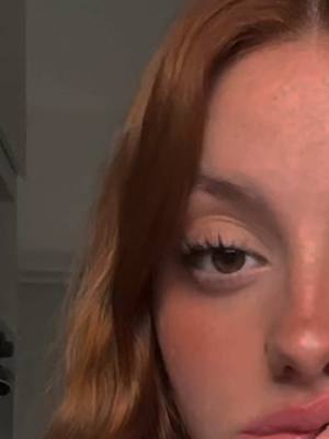 The cover image shows a close-up of a person's face, specifically focusing on the eye, part of the nose, and lips. The person has reddish-brown hair and fair skin with some visible freckles. The lighting is soft, possibly natural, giving the image a warm tone. The person's eye has long lashes and a dark iris, the lips are a shade of pink, and the skin has a slight blush. The overall composition is simple, with a focus on the facial features against a neutral background.