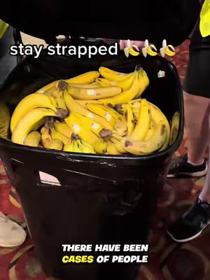 A large, black trash bin overflowing with ripe yellow bananas is the central focus, set against an indistinct background with visible legs and shoes of several people. Text overlays indicate that the video is a reference to the animated movie "Minions."