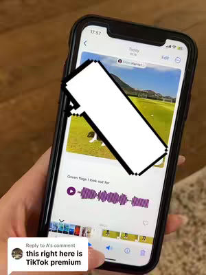 A hand holding a phone, displaying a video editing app interface. The phone screen has a blanked-out section obscuring part of video footage. A comment bubble is visible at the bottom with text. The background is a mottled surface.