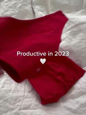 A shot of red lingerie laid on a white bedsheet, with the text 'Productive in 2023' overlaid, accompanied by a white heart symbol.