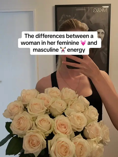 A woman is shown holding a large bouquet of light-colored roses, possibly cream or pale pink, in front of a mirror. A text overlay is displayed at the top, partially obscuring the woman's face which is also obscured by her phone, suggesting it is a selfie. The composition has a simple, soft aesthetic, with the roses being the central visual element.