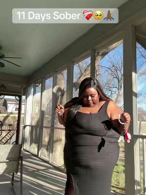 A woman in a black dress stands on a porch, windows, and tree branches in the background. Text overlay reads '11 Days Sober'.