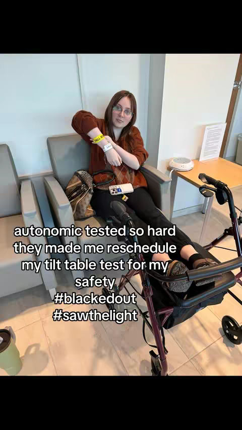 The cover image shows a woman seated in a medical setting, likely a clinic. She's wearing a brown sweater and glasses, with long hair. She has a hospital wristband. Text overlays inform viewers about the content, while a walker sits nearby, indicating potential mobility issues relevant to the context.