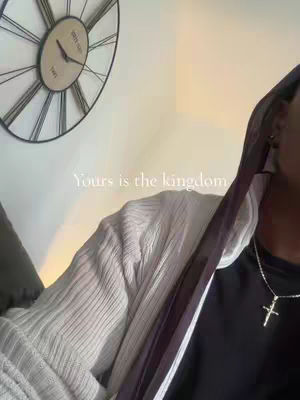 The cover image captures a portion of a room with a large analog clock on the wall and part of person who is wearing a hoodie and a cross necklace, also a text overlay that says: "Yours is the kingdom". The color palette is muted, with the dominant colors being white and black.