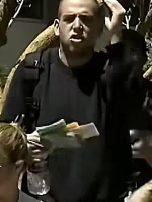 The cover image shows a man, likely the video's creator, outdoors. He is fair-skinned with short hair, looking toward the camera. His right hand is raised, as if adjusting his hair. The background is slightly blurred with hints of green foliage. The man holds some papers. The image is lit with natural light, and the composition is casual.