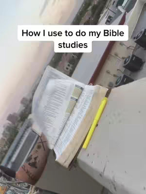 A person's open Bible rests on a ledge, with a yellow highlighter pen beside it. The background suggests a rooftop or outdoor setting.