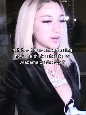 The image features a young woman with blonde hair and heavy makeup, centered in the frame. Text overlays are present, and she appears to be speaking. The background is dark and out of focus.