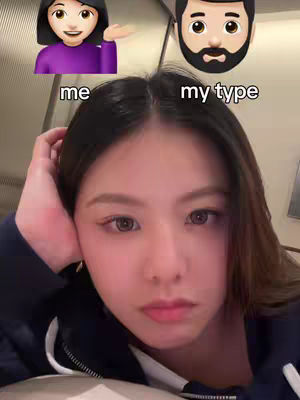 A selfie-style image with a woman in the foreground, framed from the chest up. The woman is looking down at the camera with a neutral expression; her arm is supporting her head. Overlayed are two emoji-style images above the woman's head. The top left is a female emoji, and the top right is a male emoji. Below the emojis, the text "me" and "my type" are showing in the same order.