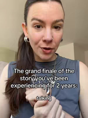 A woman with visible skin, hoop earrings, and a necklace, facing forward and speaking. Text overlays on the image. The background appears to be indoors.