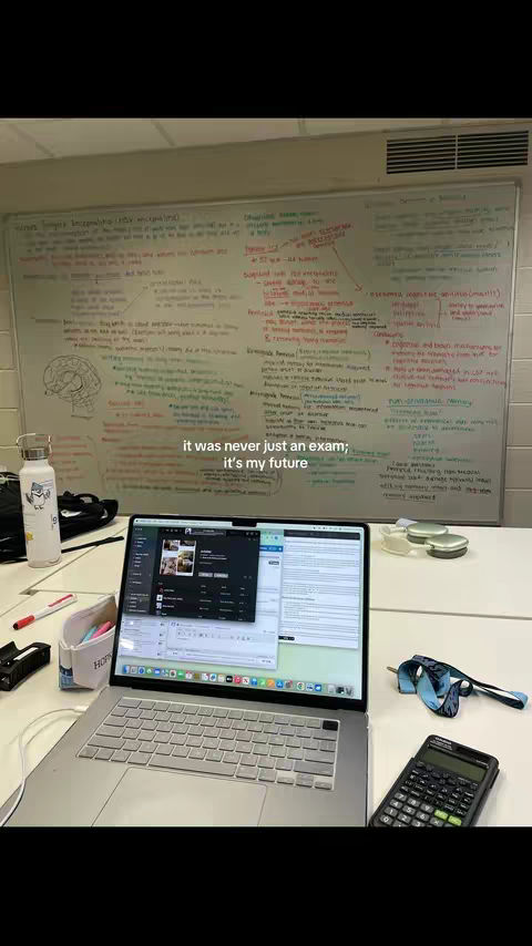 A desk with a laptop, notes on a whiteboard, and other study materials, creating a study environment.