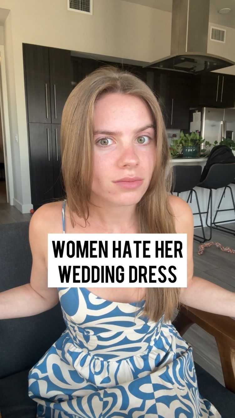 A woman with long brown hair looks at the camera with a neutral expression. She is wearing a blue and white patterned dress. A text overlay reads "WOMEN HATE HER WEDDING DRESS". The background shows a modern interior with dark cabinets and a range hood.