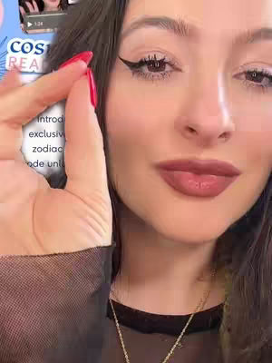 A close-up shot of a woman's face with a vibrant, red-painted fingernail near her cheek and lips. She has dark hair, well-defined winged eyeliner, and full, colored lips. To the side, a blurred app interface with text is visible. The woman is holding the red fingernail near her face.