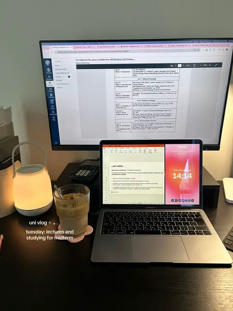 A top-down view of a desk setup with a computer monitor displaying a syllabus, a laptop showing a notes, a lamp, a beverage, and other desk accessories. The overall aesthetic is clean and modern.