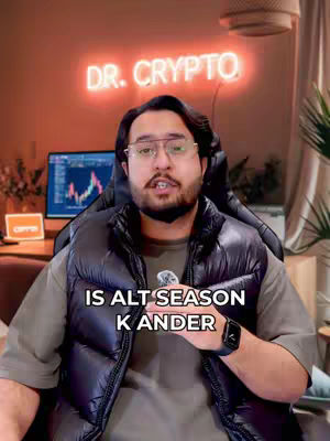 The image captures a man in a modern, indoor setting. He is the central focus, wearing a black puffer vest over a light-colored shirt. He has short dark hair, glasses, and a beard. The background contains a neon sign that reads 'DR. CRYPTO' glowing brightly. A computer screen with a chart is also visible. The overall composition has a professional and informative tone.