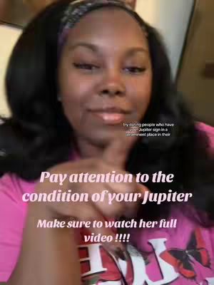 A selfie-style video cover featuring a dark-skinned woman with long, dark hair and a headband. She points to the text overlaid on the video suggesting the topic of the video is about Astrology. The background is a blurred indoor setting. Text overlays in the image state, "Pay attention to the condition of your Jupiter, try dating people who have your Jupiter sign in a prominent place in their Make sure to watch her full video !!!".