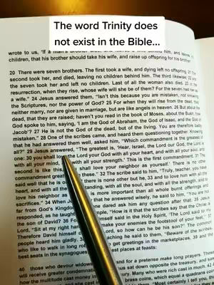 The image shows an open book with printed text, a pen pointing towards the text, and an overlaid text label at the top that reads "The word Trinity does not exist in the Bible...". The book's pages are yellowed, and the pen's tip rests near the words. The composition suggests a focus on a specific passage or argument.
