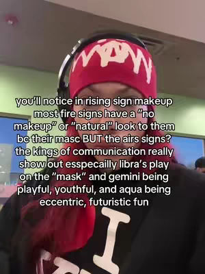 The cover image features a person from the chest up, wearing a red beanie with a white design in a room setting. The individual has headphones on and facial hair is visible. Text overlays discuss makeup for rising signs, linking to astrological concepts. The lighting is soft, and the composition is straightforward.