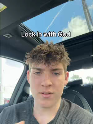 A young man is seated inside a car, looking towards the camera with a serious expression. The car's interior is visible, along with a portion of the sky through the sunroof. Above the man, text overlays the image.