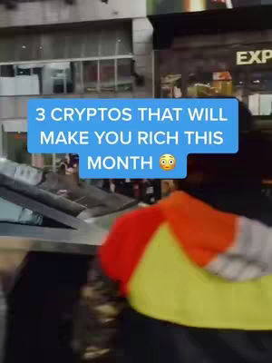 A person is seen from behind in a city setting, with a blue rectangular text overlay that reads, "3 CRYPTOS THAT WILL MAKE YOU RICH THIS MONTH 😲". The person is wearing a yellow and orange jacket, and the background shows buildings and reflections.