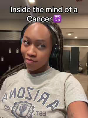 A selfie-style shot features a Black woman with dreadlocks, wearing headphones, and a light gray t-shirt with the word "ARIZONA" prominently displayed. The background appears to be a gym or public restroom setting. Text overlays at the top read "Inside the mind of a Cancer" accompanied by a Cancer zodiac symbol.