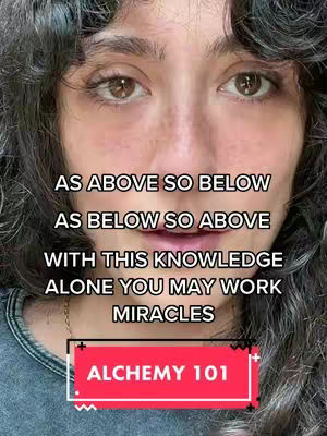 A close-up shot of a woman's face with brown eyes, dark curly hair framing her face, and text overlays providing context. The woman has a neutral expression, with a glimpse of a necklace. The image uses a soft color palette, with the text overlays in white and red against a black background. The background appears to be a wall.