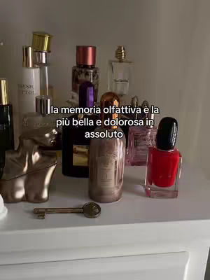 A display of various perfume bottles and a red nail polish bottle, set on a white surface. A key lies in front of the bottles, while text overlays.
