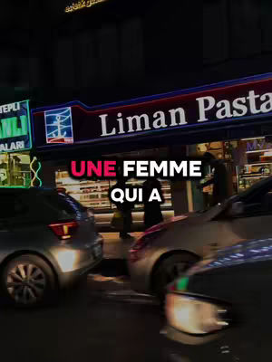 The cover image shows street scene. The main focus is on a building with bright sign that is a restaurant. At the bottom, there is a text overlay that says "UNE FEMME QUI A". In the front of the restaurant, there are two cars blurred. It is evening, and the scene is lit by the building's neon lights, with the overall color palette being dark, dominated by the night.
