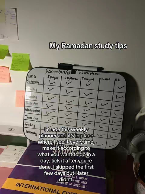 A vertical shot of a study desk featuring a weekly planner, a textbook, and some sticky notes. The planner is a white board with a grid, the textbook, and some sticky notes attached to the wall. Text overlay indicates this is about study tips for Ramadan.