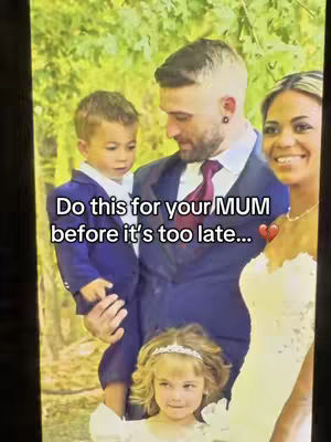 A family portrait featuring a man holding a young boy, with a woman and another young girl in the foreground. The man is wearing a suit and tie, and the woman is wearing a dress, suggesting a wedding or formal event. The background is blurred, suggesting an outdoor setting.