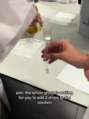 The cover image shows a hands-on experiment in a lab setting. A person wearing a lab coat is pouring a yellow liquid from a small bowl into a clear test tube held by another person's hand. The background includes a white surface and other lab equipment. The text overlay indicates a point of view.