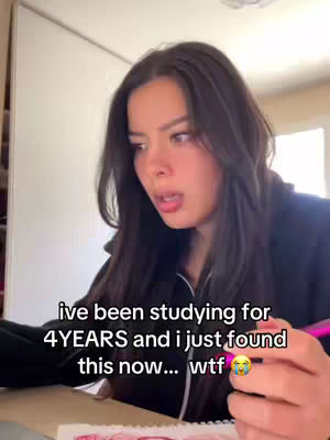 A young woman with long dark hair looks down with a surprised expression, holding a pen and notebook. Text overlayed on the image reads: 'ive been studying for 4YEARS and i just found this now... wtf π'. The background is a room with a window.