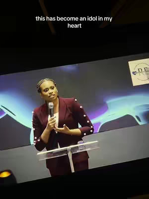 The cover image shows a woman in a maroon blazer speaking at a podium, with a soft-focus background. Above the woman is the text overlay "this has become an idol in my heart".
