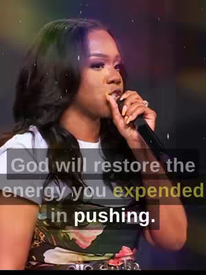 A woman with long, dark hair is speaking into a microphone. She is wearing a white top under a floral print garment. Text is overlaid on the image, and the background has a colorful, blurred appearance.