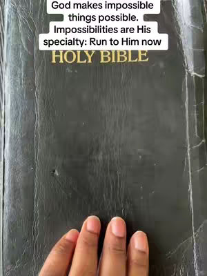The cover image is a close-up shot focusing on a slightly open, black Holy Bible. The top portion displays white text with a black outlined box, presenting the message 'God makes impossible things possible. Impossibilities are His specialty: Run to Him now'. Below this, the embossed gold lettering 'HOLY BIBLE' is visible. A hand with neatly manicured nails is at the bottom.