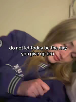 The image shows a person, appearing to be a young woman, partially visible in a soft focus. She is wearing a purple sweatshirt with text or details visible on the left side. The overlay text is in white, placed over her face, and contains inspirational words. The background is a beige/cream color.
